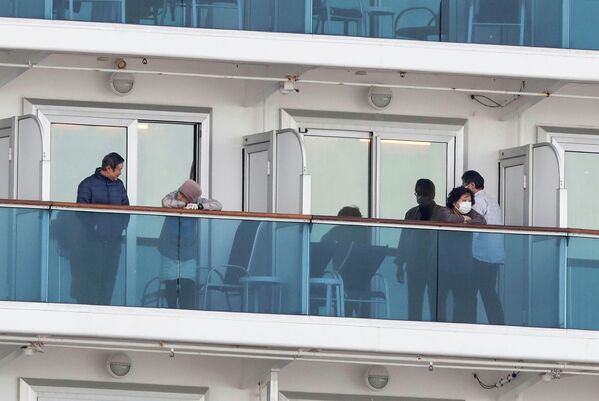 Пассажиры на палубе круизного судна Diamond Princess в порту Йокогамы Пассажиры на палубе круизного судна Diamond Princess в порту Йокогамы