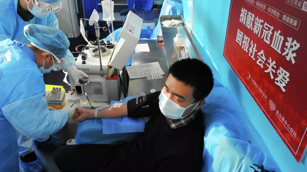 Пациент, выздоровевший после заболевания коронавирусом, сдает кровь в больнице китайского города Ляньюньган