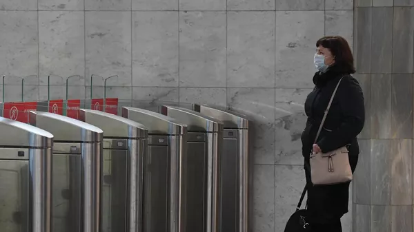 Женщина в медицинской маске на входе в Московский метрополитен