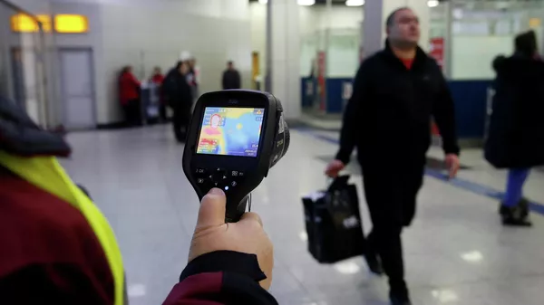 An employee of the sanitary-epidemiological service of Kazakhstan checks the temperature of passengers at the airport of Almaty with a thermal imager An employee of the sanitary-epidemiological service of Kazakhstan checks the temperature of passengers at the airport of Almaty with a thermal imager