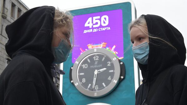 Девушки в медицинских масках рядом с часами обратного отсчета времени до старта чемпионата Европы по футболу