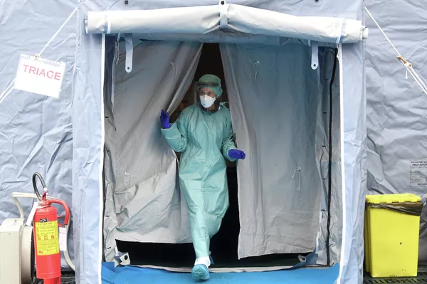 Медицинский работник у входа в больницу Spedali Civili в городе Брешиа, Италия