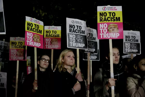 Участники акции протеста с плакатами Нет расизму. Нет Трампу