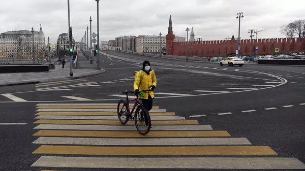 Сотрудник службы доставки Яндекс-Еда на пешеходном переходе улицы Варварка во время режима самоизоляции жителей