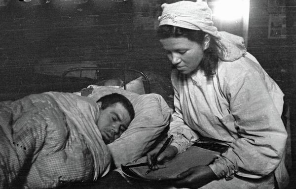 Сестра медсанбата пишет письмо родным под диктовку раненого солдата. 1-ый Прибалтийский фронт Сестра медсанбата пишет письмо родным под диктовку раненого солдата. 1-ый Прибалтийский фронт