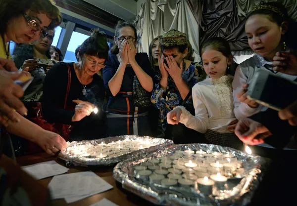 Женщины зажигают свечи в Новосибирском еврейском общинном культурном центре перед началом пасхального седера во время иудейского праздника Песах