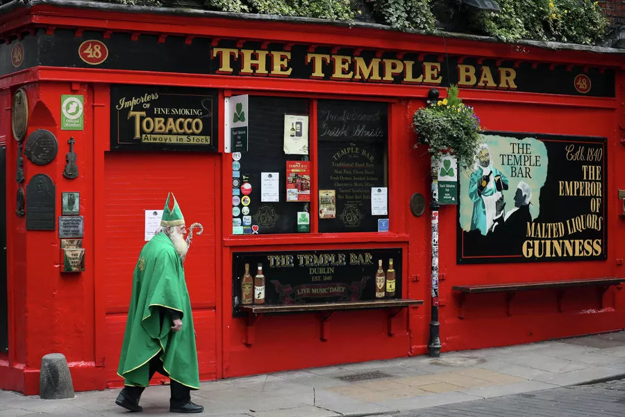 Мужчина в костюме Святого Патрика проходит мимо паба в Дублине 