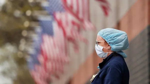 Медсестра в защитном снаряжении у больницы Элмхерст в районе Квинс в Нью-Йорке