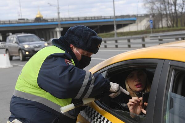 Инспектор дорожно-патрульной службы проверяет у пассажира такси цифровой пропуск на передвижение по Москве Инспектор дорожно-патрульной службы проверяет у пассажира такси цифровой пропуск на передвижение по Москве