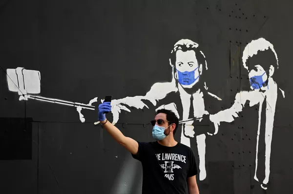 Мужчина делает селфи на фоне граффити с изображением актеров Джона Траволты и Сэмюэля Джексона  в Мадриде 