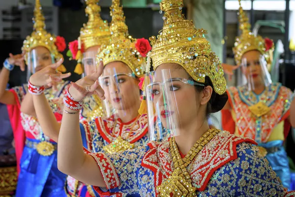 Танцоры выступают в защитных масках в храме Эваран в Таиланде