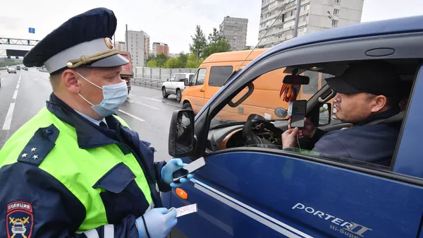 Инспектор ДПС проверяет цифровой пропуск у водителя Инспектор ДПС проверяет цифровой пропуск у водителя