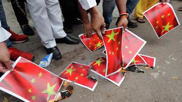 Индийцы сжигают листы бумаги с изображением флага Китая в Лакхнау 