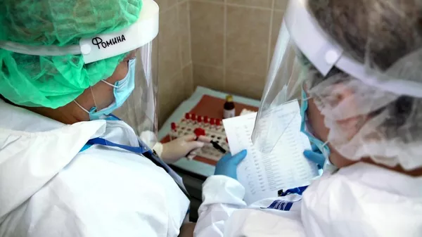 Врачи складывают пробирки с кровью для анализа перед выпиской добровольцев испытаний вакцины от коронавируса в Главном военном клиническом госпитале имени Н. Н. Бурденко