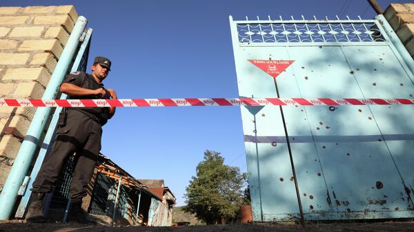 Сотрудник правоохранительных органов охраняет двор с не взорвавшимся снарядом после обстрела со стороны Армении в деревне Агдам, Азербайджан Сотрудник правоохранительных органов охраняет двор с не взорвавшимся снарядом после обстрела со стороны Армении в деревне Агдам, Азербайджан