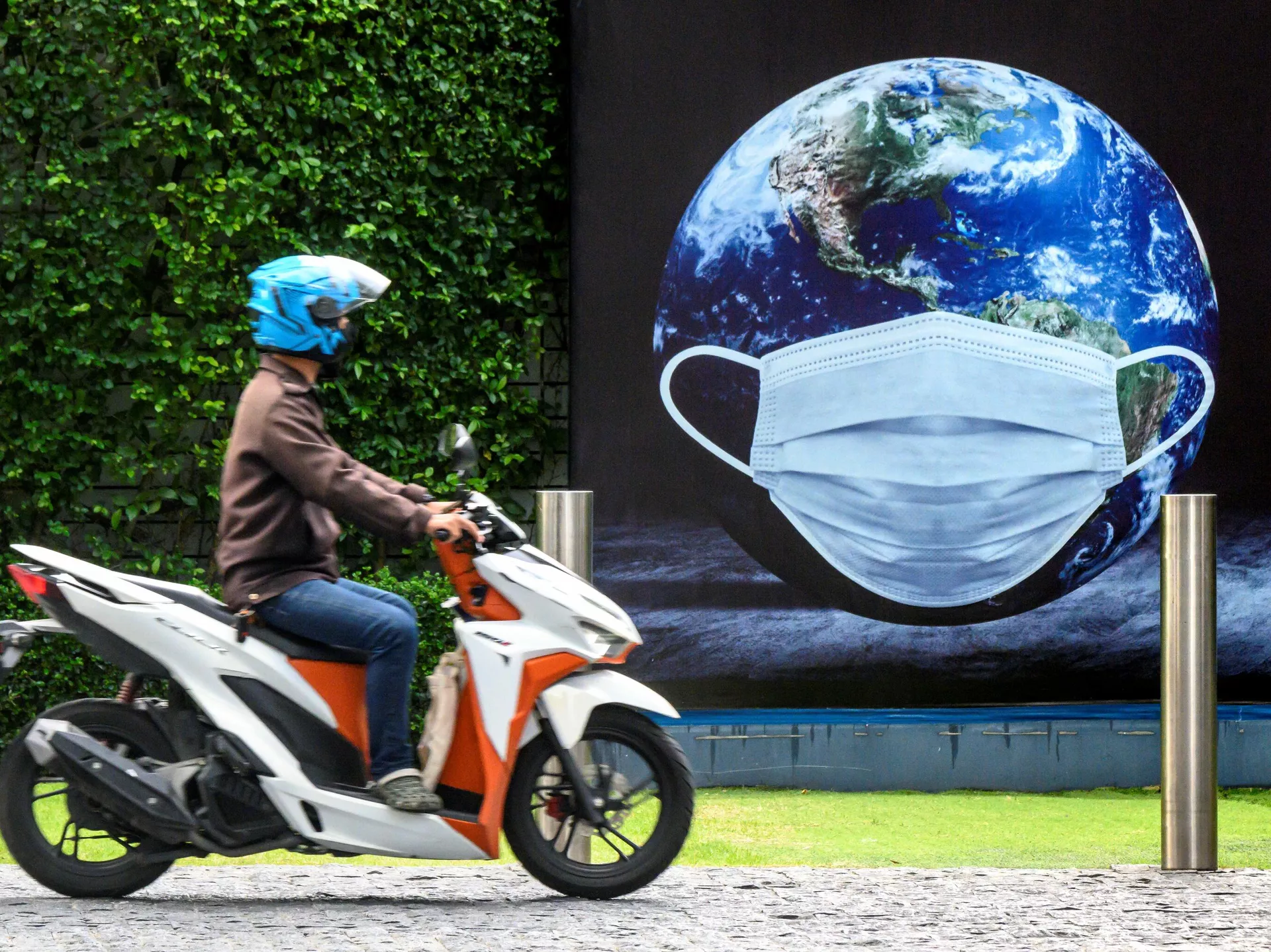 Мужчина на скутере у плаката в Бангкоке