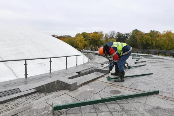 Рабочий устанавливает ограждение вокруг фонтана после демонтажа в парке Царицыно в Москве