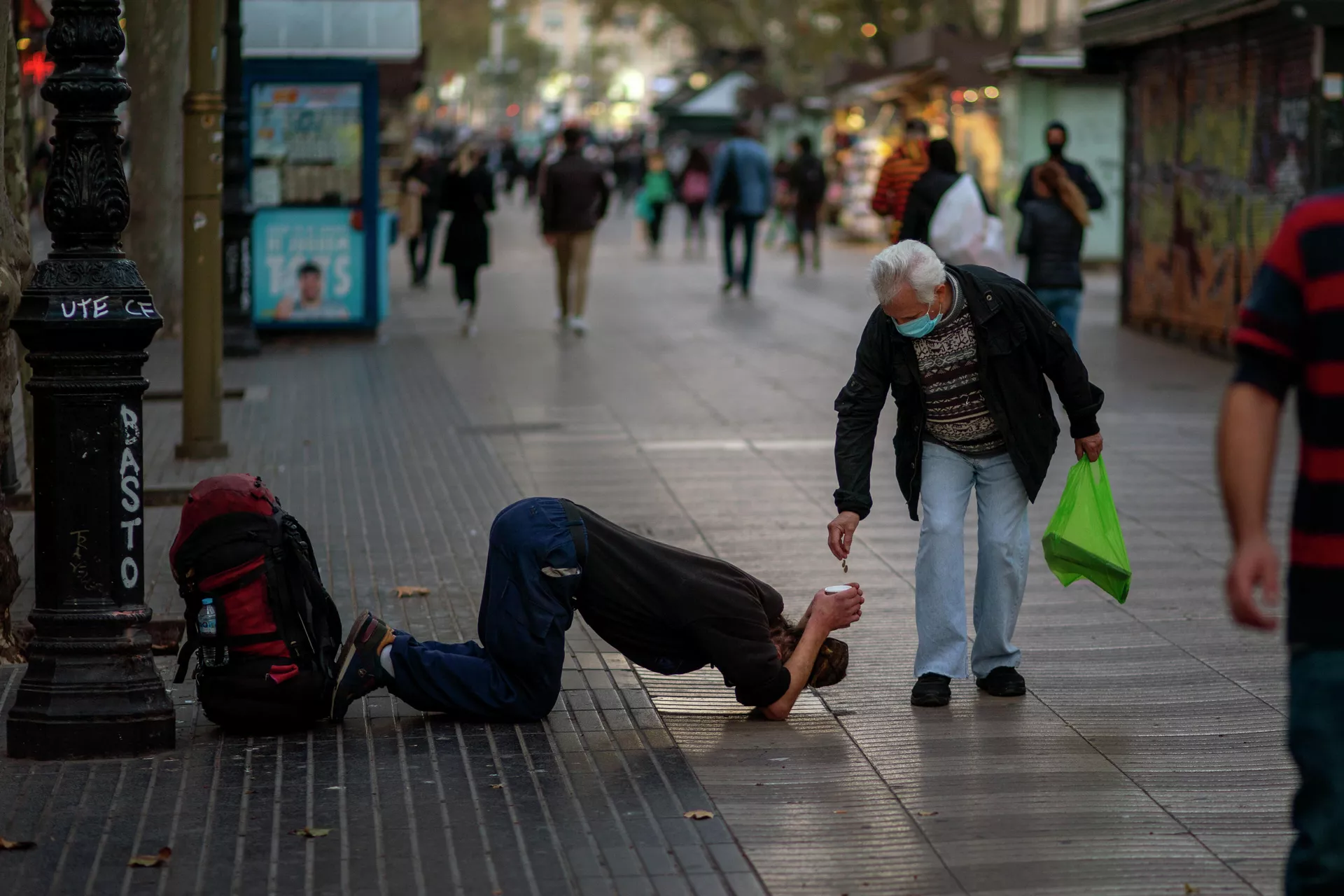 Мужчина подает милостыню нищему на бульваре Рамблас в Барселоне - РИА Новости, 1920, 17.11.2020