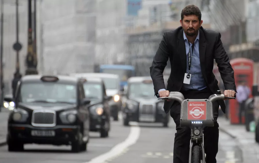 Мужчина едет на велосипеде по улице Лондона