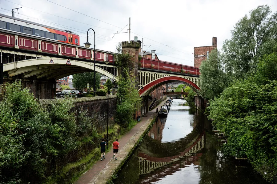 Прохожие на набережной канала в районе Каслфилд в Манчестере