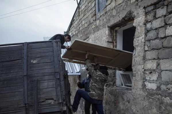 Мужчины загружают дверь в кузов грузового автомобиля в поселке Карегах в Нагорном Карабахе