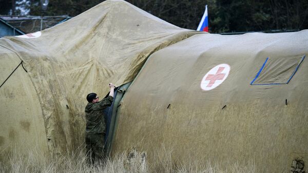Российская военнослужащая закрепляет тент на каркасном модуле на территории мобильного полевого госпиталя неподалеку от Степанакерта Российская военнослужащая закрепляет тент на каркасном модуле на территории мобильного полевого госпиталя неподалеку от Степанакерта