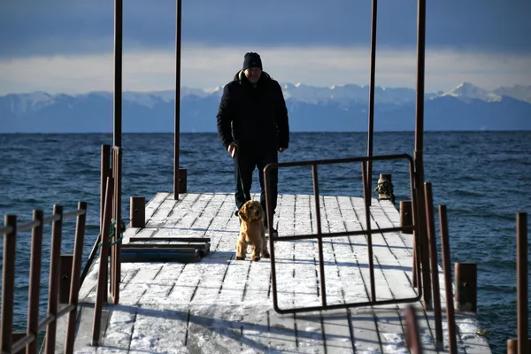 Мужчина с собакой на причале озера Байкал