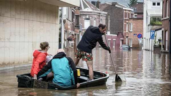Люди плывут на лодке по жилой улице после наводнения в Англере, провинция Льеж, Бельгия