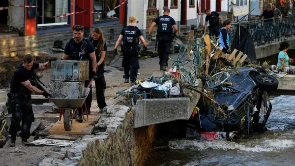 Полицейские и волонтеры убирают завалы в районе, пострадавшем от наводнения в Бад-Мюнстерайфеле, Германия