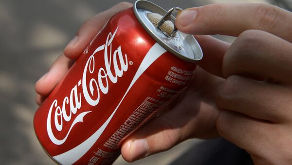 Покупатель держит банку с напитком компании Coca-Cola. архивное фото Покупатель держит банку с напитком компании Coca-Cola. архивное фото