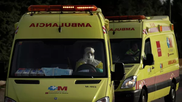 Водитель скорой помощи в защитном костюме везет пациента в больницу в Мадриде