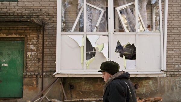 Женщина идет возле поврежденного дома в Дебальцево. Архивное фото Женщина идет возле поврежденного дома в Дебальцево. Архивное фото