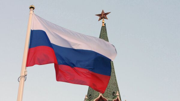 Российский государственный флаг на фоне кремлевской башни. Архивное фото Российский государственный флаг на фоне кремлевской башни. Архивное фото