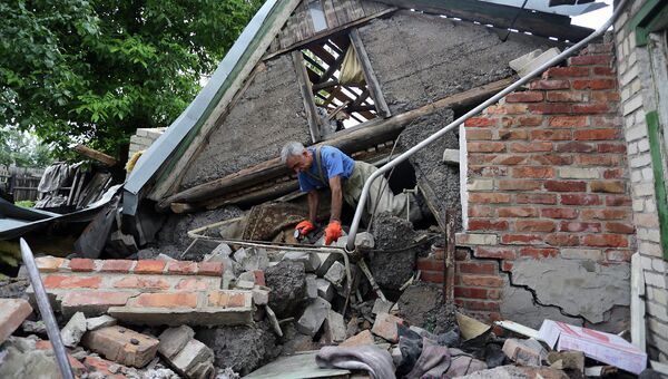 Спасатель возле разрушенного в результате обстрела дома в поселке Гольмовский Донецкой области. Архивное фото Спасатель возле разрушенного в результате обстрела дома в поселке Гольмовский Донецкой области. Архивное фото