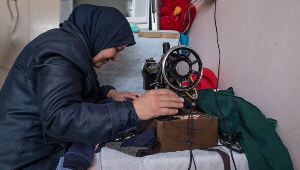 Женщина штопает одежду в лагере беженцев, размещенном в здании одной из школ Дамаска Женщина штопает одежду в лагере беженцев, размещенном в здании одной из школ Дамаска