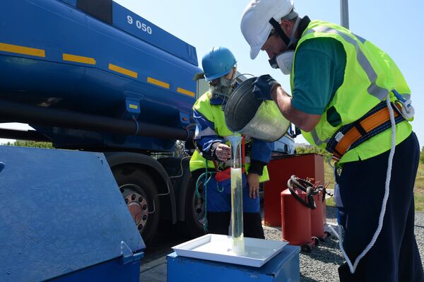 Сотрудники АЗС берут пробу бензина во время приемки бензовоза Сотрудники АЗС берут пробу бензина во время приемки бензовоза