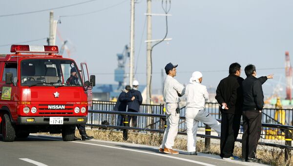 Пожарные и местные жители смотрят на море после предупреждения о возможном цунами в городе Сома, Япония Пожарные и местные жители смотрят на море после предупреждения о возможном цунами в городе Сома, Япония