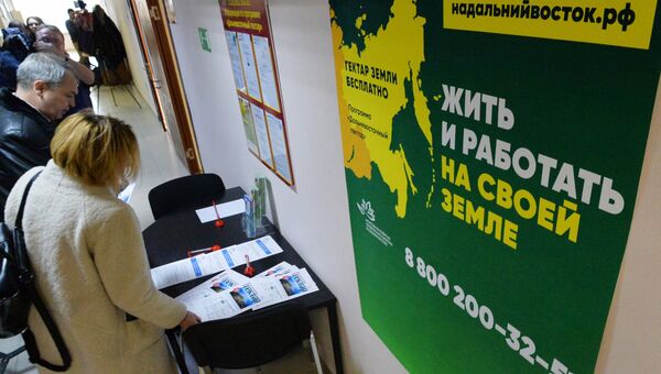 Посетители возле стенда с информационными буклетами о дальневосточном гектаре. Архивное фото Посетители возле стенда с информационными буклетами о дальневосточном гектаре. Архивное фото