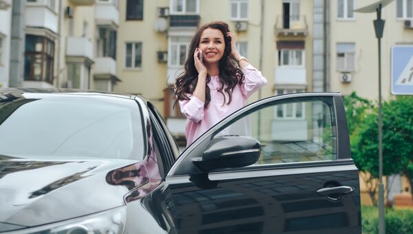 Девушка разговаривает по телефону возле автомобиля. Архивное фото Девушка разговаривает по телефону возле автомобиля. Архивное фото