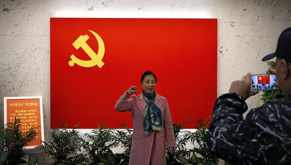 Женщина фотографируется у флага Коммунистической партии Китая в Шанхае Женщина фотографируется у флага Коммунистической партии Китая в Шанхае
