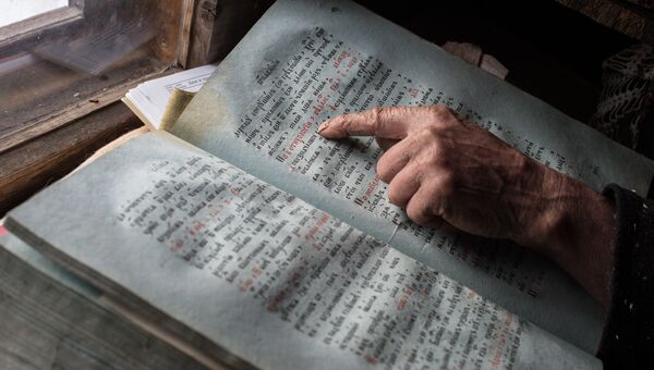 Агафья Лыкова показывает книги, оставшиеся ей от родителей.