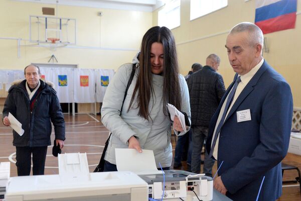 Девушка опускает бюллетень в урну на выборах президента РФ на избирательном участке во Владивостоке. Девушка опускает бюллетень в урну на выборах президента РФ на избирательном участке во Владивостоке.