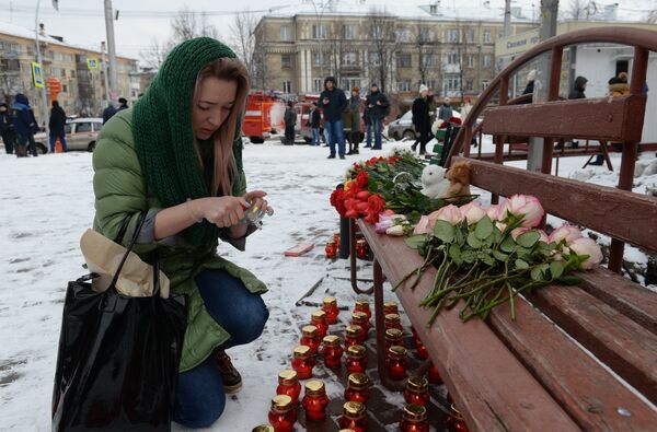 Женщина зажигает свечу возле здания торгового центра «Зимняя вишня» в Кемерово, где произошел пожар Женщина зажигает свечу возле здания торгового центра «Зимняя вишня» в Кемерово, где произошел пожар