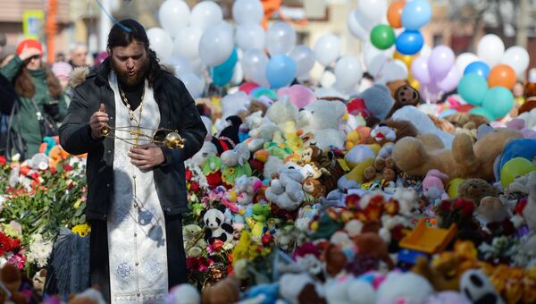 Священнослужитель у мемориала из цветов и воздушных шаров в память о жертвах пожара в торгово-развлекательном центре Зимняя вишня в Кемерово Священнослужитель у мемориала из цветов и воздушных шаров в память о жертвах пожара в торгово-развлекательном центре Зимняя вишня в Кемерово