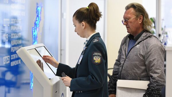 Сотрудница помогает посетителю со сдачей налоговой отчетности. Архивное фото Сотрудница помогает посетителю со сдачей налоговой отчетности. Архивное фото