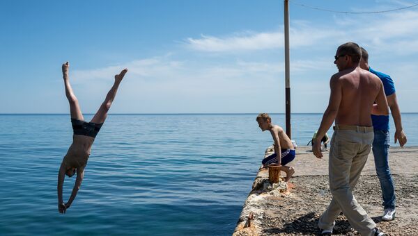 Отдыхающий прыгает с пирса в море в Новом Свете Отдыхающий прыгает с пирса в море в Новом Свете