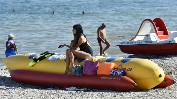 Отдыхающие загорают на пляже Коктебеля на берегу Черного моря