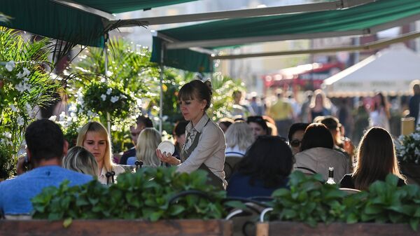 Посетители в летнем кафе в Климентовском переулке в Москве
