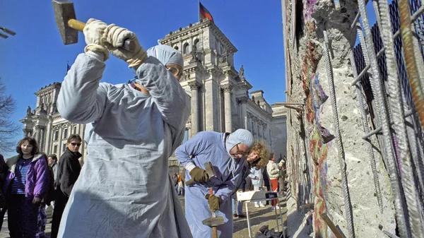 Жители ГДР разбирают Берлинскую стену на сувениры