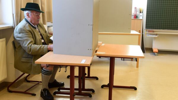 Мужчина в традиционной баварской одежде заполняет бюллетень для голосования на избирательном участке в Нойкирхене, Германия. 14 октября 2018 Мужчина в традиционной баварской одежде заполняет бюллетень для голосования на избирательном участке в Нойкирхене, Германия. 14 октября 2018